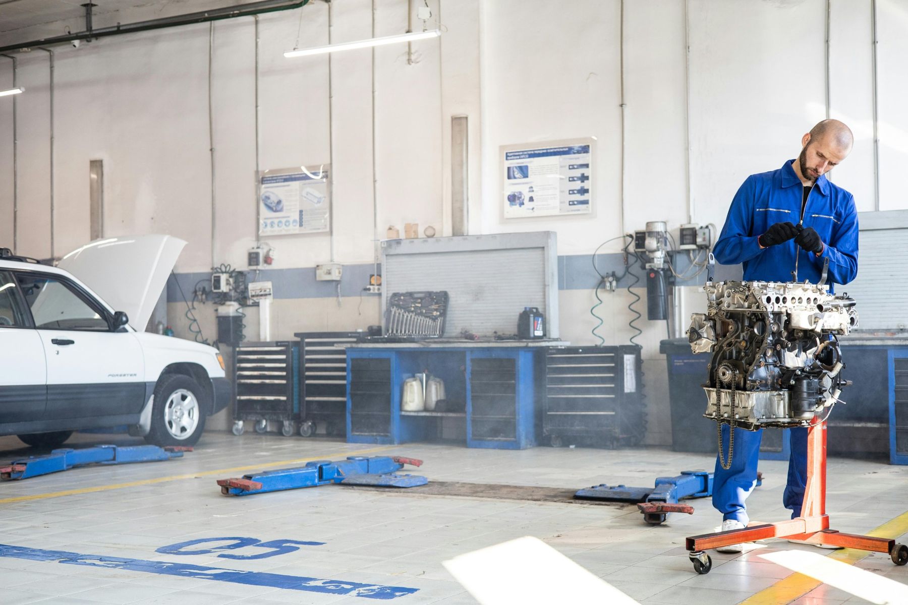 Mechaniker arbeitet in heller Werkstatt an einem ausgebauten Motorblock