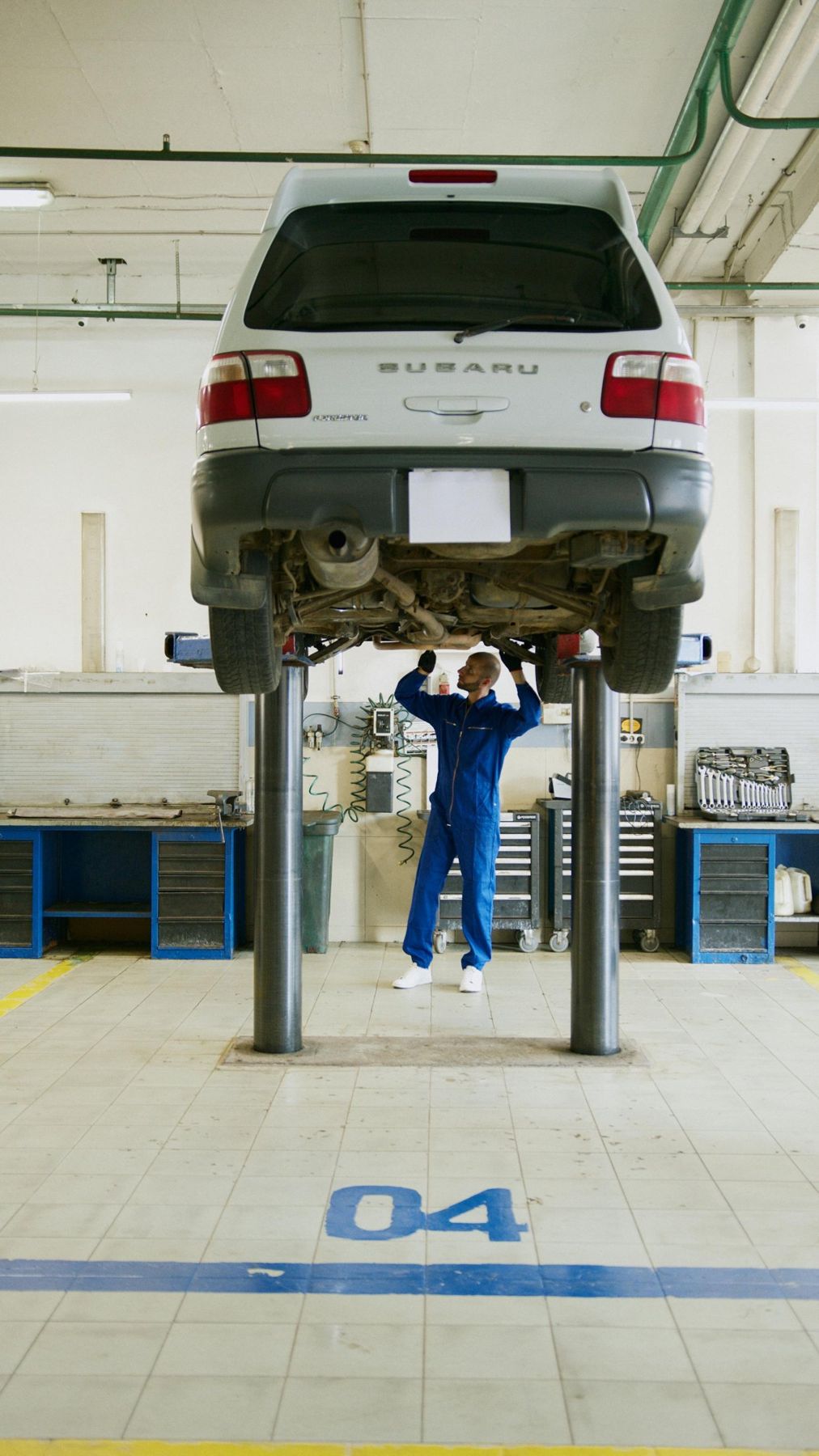 Fahrzeug auf Hebebühne in heller Werkstatt während Wartung durch Mechaniker